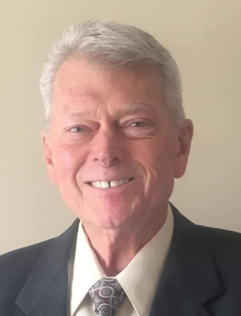 Portrait of Dr. Michael Donovan Koontz, smiling in a dark suit and patterned tie.